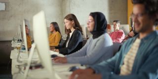 教师在大学房间里给不同种族的男女学生上课，在电脑上学习新的学术技能。讲师与聪明的青年学者分享知识。