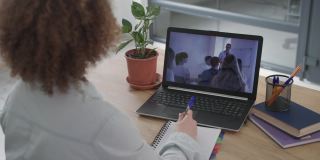 远程学习，女学生在会议期间坐在家里的桌子上通过笔记本电脑视频交流接受在线培训