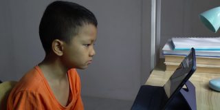 亚洲男孩在家里用平板电脑看媒体。