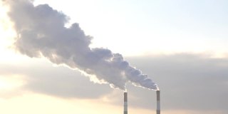 在多云的天空中冒着浓烟的工业烟囱。