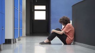悲伤的少年学生独自坐在地板上欺凌的受害者和友好的同学朋友帮助和安慰他。教育中的同理心和支持视频素材模板下载