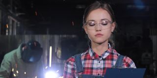 年轻女孩工程师的肖像，在制造业工厂的设备工作
