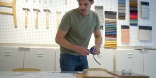 男设计师在办公室画一些草图并测量一块木板