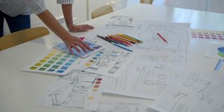 不知名的室内设计师在办公室用平板电脑和彩色铅笔绘制不同的草图