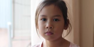 4K慢动作的快乐小混血亚洲女孩用她的手盖住她的眼睛做心形手势，捐赠，慈善，关心，爱，心脏健康，社会距离概念
