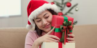 快乐美丽的亚洲女人庆祝堆放许多礼物礼盒在圣诞晚会。可爱的女孩在圣诞节假期拿着用丝带和蝴蝶结装饰的礼盒。春节快乐。
