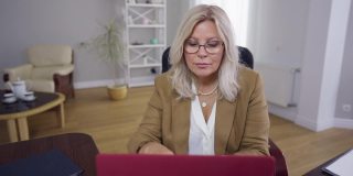 前视图肖像集中集中的女人在眼镜坐在桌子与笔记本电脑阅读创新新闻。白人心理学家在室内在线研究创新。