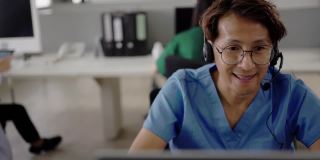 亚洲医生在呼叫中心办公室的电脑上对病人进行远程健康咨询。
