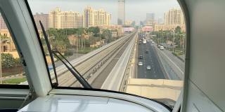 这列单轨列车在阿联酋迪拜的玻璃摩天大楼之间穿梭。无人驾驶的列车。从车外透过挡风玻璃看