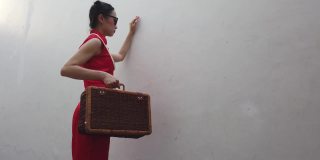 图为，在户外拍摄《时尚旗袍》时，背着行李戴着墨镜的中国年轻女子。