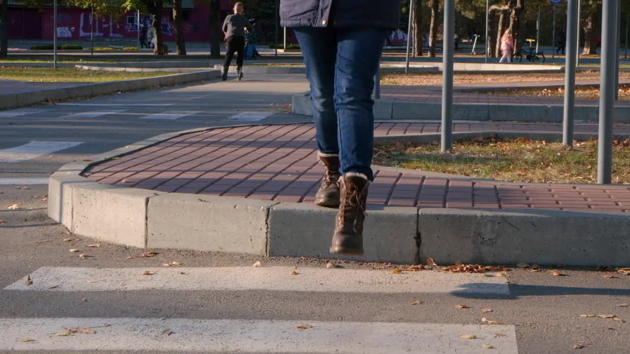 一个穿棕色鞋子的女人在人行横道过马路，两腿特写。