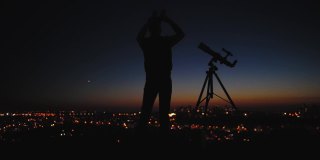 一个人的剪影，望远镜和城市街灯下的星空。