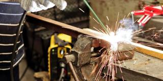 电影:工业工人在金属加工厂使用现代焊机焊接金属结构。炽热的金属发出火花。