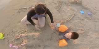 亚洲的孩子们微笑着在沙滩上玩沙子