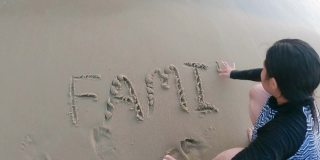 亚洲女孩在沙滩上写东西