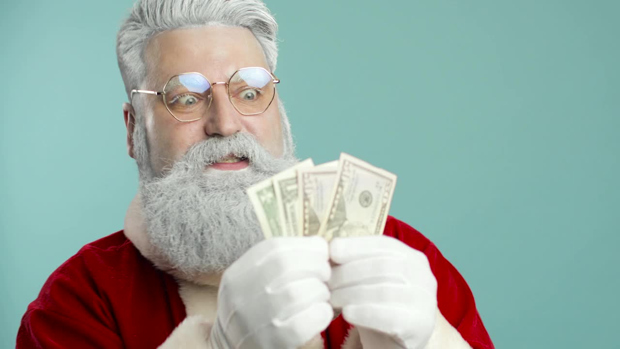 有趣的时尚圣诞老人在蓝色背景与金钱摆姿势。金融、钱,钞票。特写镜头