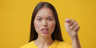 愤怒的韩国女性用手指指责某人，黄色背景