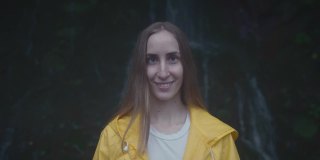 白种人女孩的肖像旅行者在森林瀑布附近的黄色雨衣。生活方式的概念，慢动作