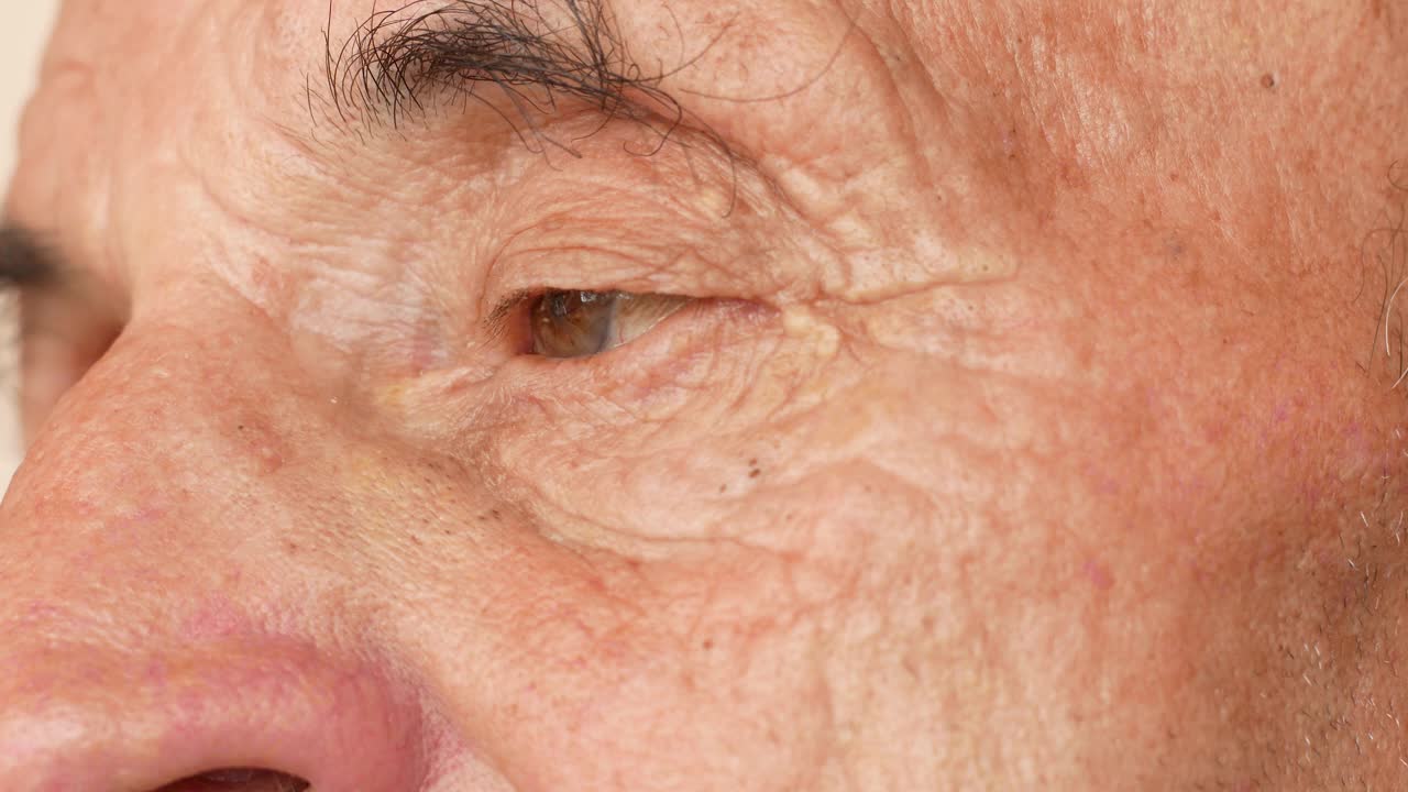 一个忧郁的老人的特写镜头。70岁以上的老年白人男性的眼睛有皱纹。生活经验。领养老金的人思考人生。选择性对焦，景深浅