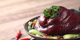 用勺子将香喷喷的酱油倒在盘子里的台湾红烧猪腿肉上。