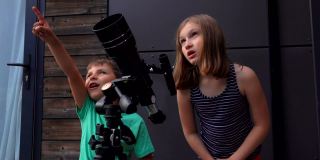 一个可爱的女孩和她的小弟弟在安装望远镜