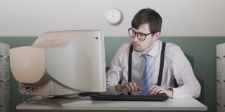 一个愤怒的人正在办公室用手敲打旧电脑。