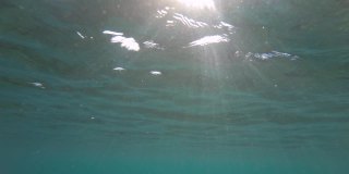 抽象的海洋背景视图，从水下的反射，表面的波浪和阳光的光芒耀眼和闪闪发光