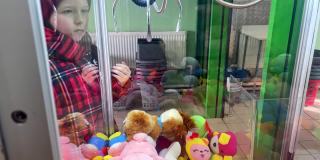 一个白人小女孩在商场里玩抓软玩具的抓娃娃游戏。不成功的获奖尝试，失败，生活方式