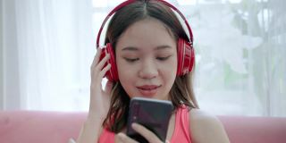 一名身穿运动服的年轻亚洲女子在锻炼间歇使用智能手机和耳机使用社交媒体。