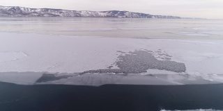 冻结贝加尔湖。贝加尔湖进入冬眠。贝加尔斯克冰冷的海岸，可以看到群山。自然背景。季节变化。无人机射击。