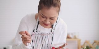 亚洲高级妇女教如何自制水果冰沙与不同的口味，草莓，和酸奶。健康的天然益生菌调味饮料，正面，慢镜头。