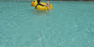 快乐的亚洲男孩和女孩一起在游泳池的黄鸭子橡皮筏上放松，与家人一起度假，生活理念。