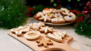 女人用白色奶油糖霜装饰雪花形状的圣诞自制姜饼饼干。厨房桌上放着圣诞糖果。传统的圣诞准备。视频素材模板下载