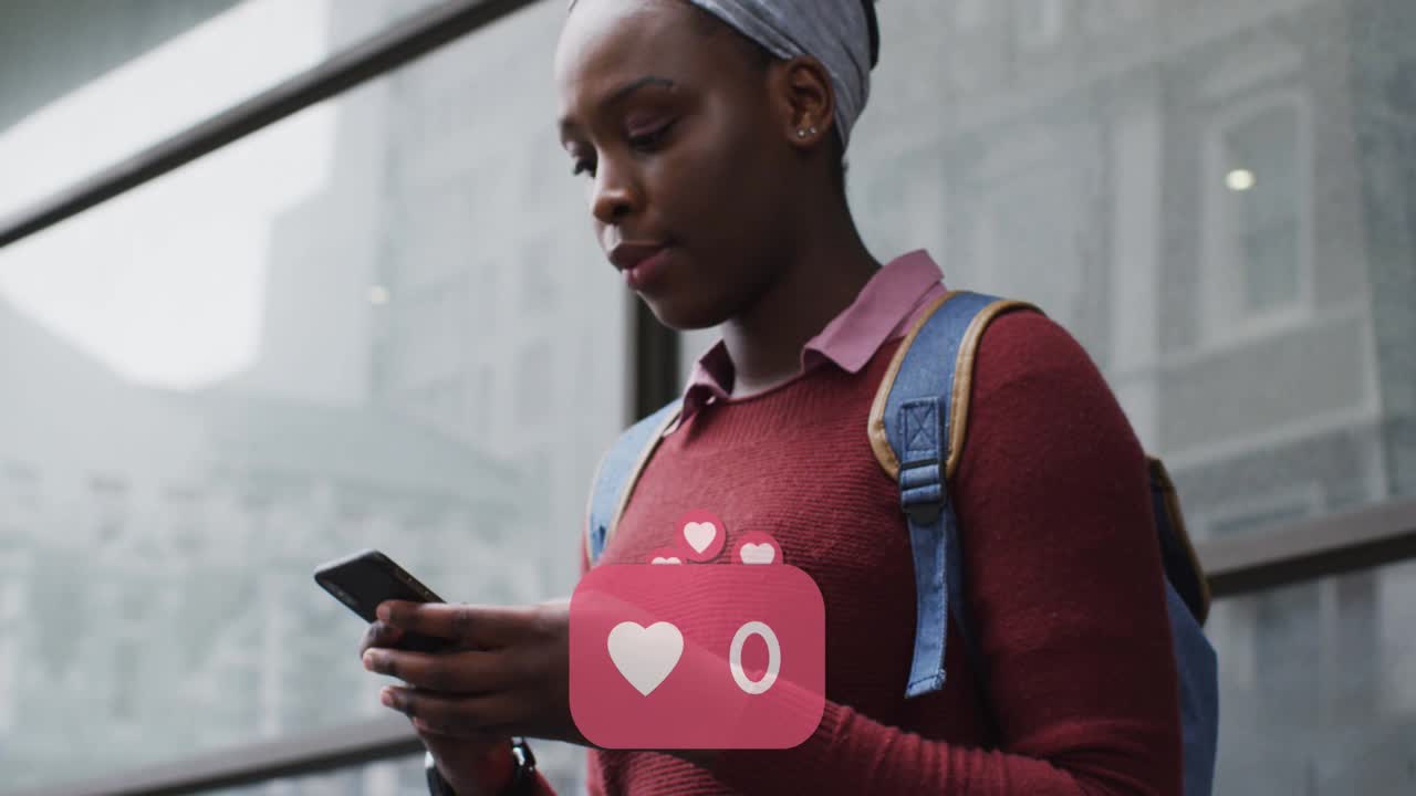 在大街上使用智能手机的微笑的非裔美国妇女的社交媒体心形图标的动画