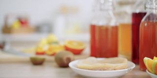 自制的发酵生康普茶与不同的调味料在一个瓶子。健康的天然益生菌调味饮料，包括配料，猕猴桃，橙子，青苹果