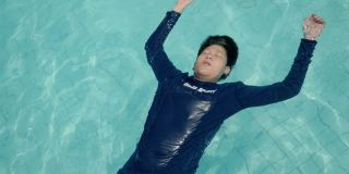 快乐的亚洲男孩回到浮在游泳池在度假酒店或度假村与家人，生活理念。