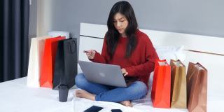 开朗的女人在床上用笔记本电脑上网购物