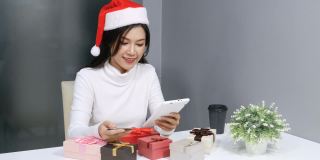 戴着圣诞帽的快乐女人在网上用电子平板电脑购买圣诞礼物