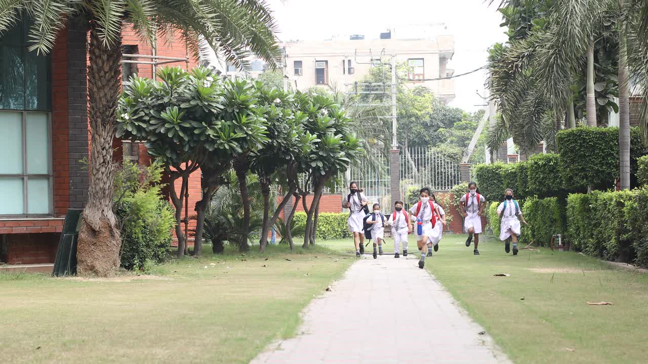 孩子们戴着防护口罩跑向学校