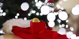 圣诞节投资，比特币在一个以圣诞树和彩灯为背景的礼品盒里