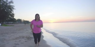暑假里，亚洲胖女人早上在沙滩上慢跑