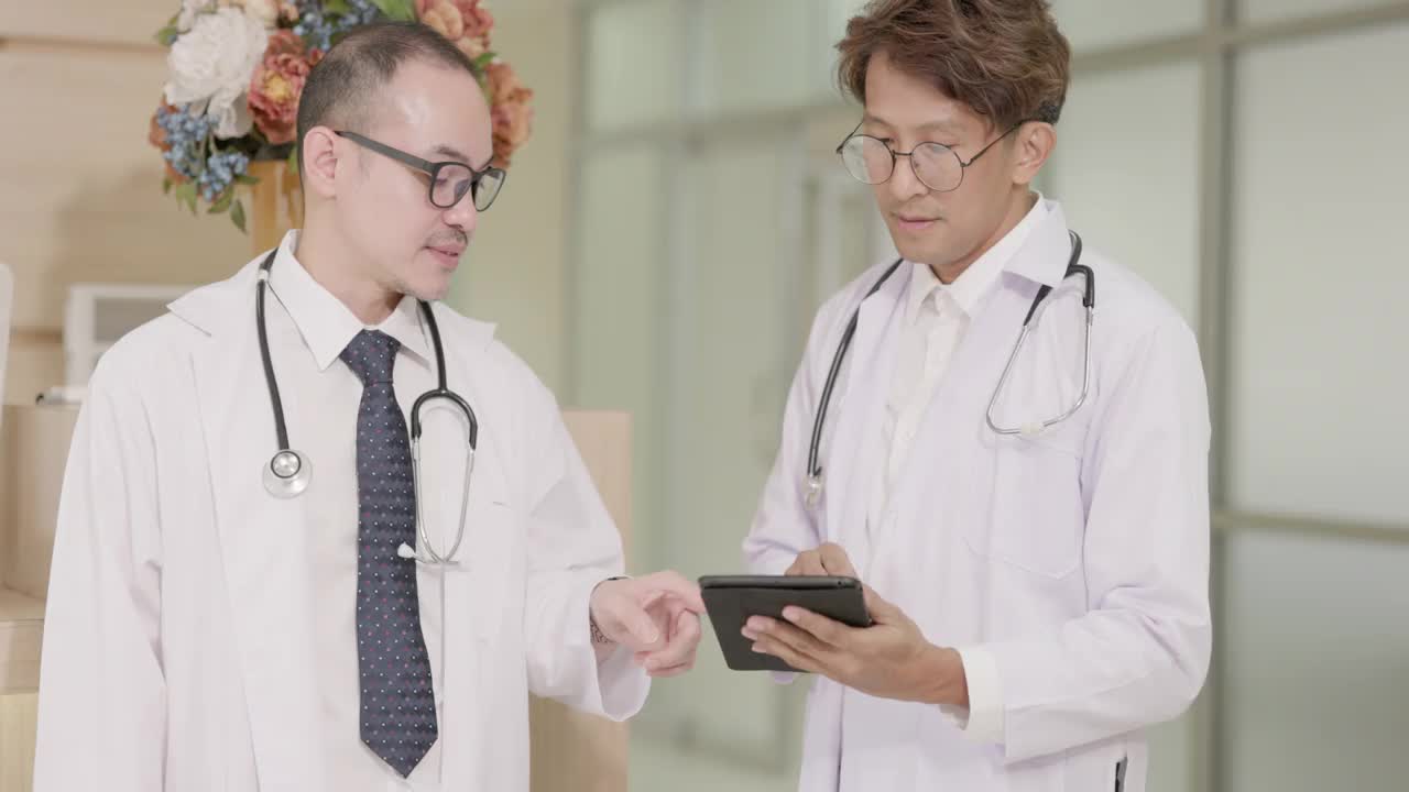 两个身穿白大褂的男医生一边交谈，一边使用平板电脑，然后握手。在医疗和医疗技术方面的合作概念