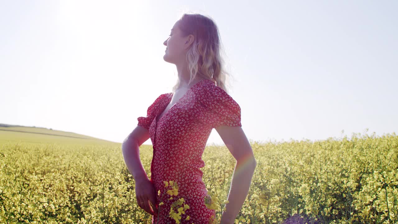 一名年轻女子在油菜花盛开的田野里放松的4k视频片段