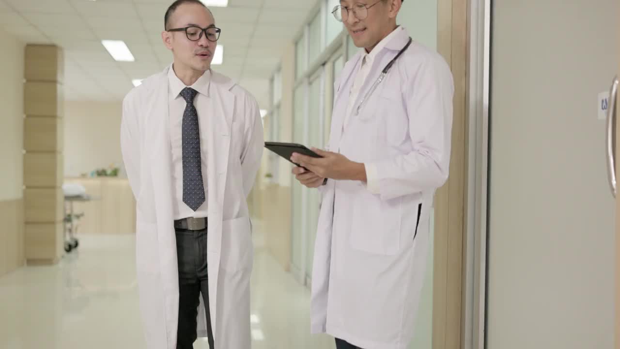 两个身穿白大褂的男医生一边交谈，一边使用平板电脑，然后握手。在医疗和医疗技术方面的合作概念