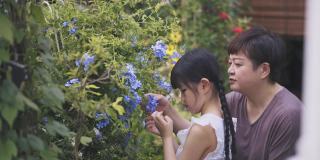 亚洲华人母亲和女儿在周末休闲活动时，在后院花园享受亲密时光