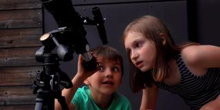 一个可爱的小女孩和她的小弟弟正在用望远镜看天空