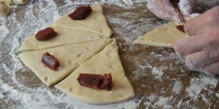 把面团揉成牛角面包的形状。自制的甜糕点。果酱，女人亲手做的面团。在家里的厨房里用手做果酱饼干