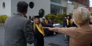大学毕业典礼后，一个快乐美丽的年轻女子兴奋地拥抱她的父母