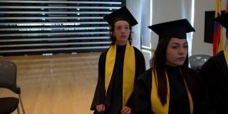 在毕业典礼上，一名自豪的女学生站起来，在领取毕业证书时向她的同学们打招呼