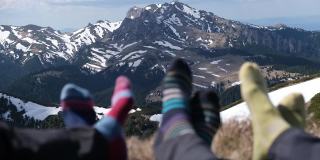详细照片与徒步旅行者的脚和他们的彩色袜子放松在山顶